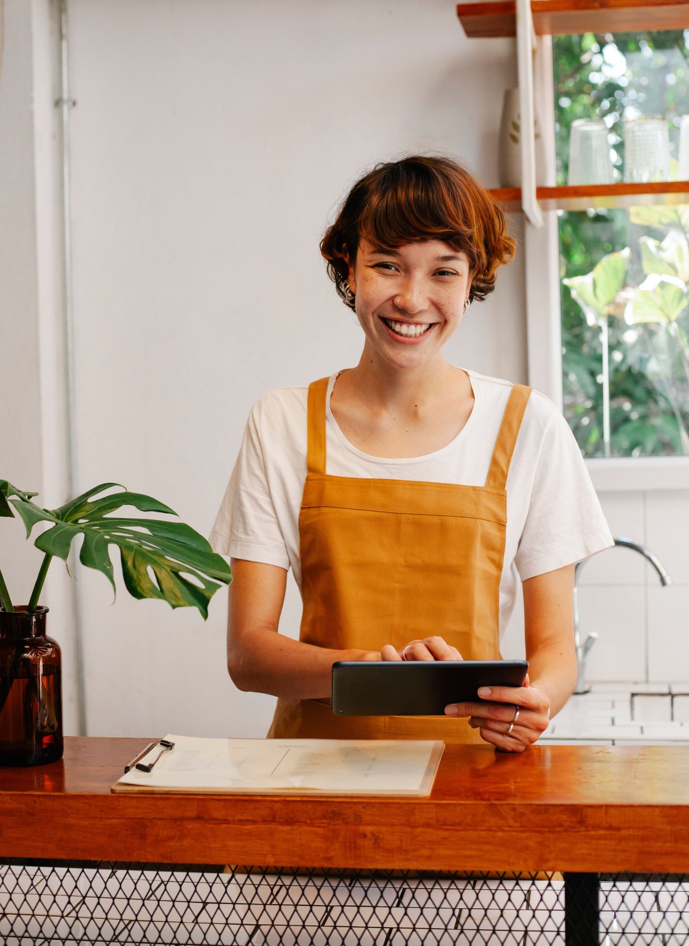 A small business owner checking orders on a tablet at the counter